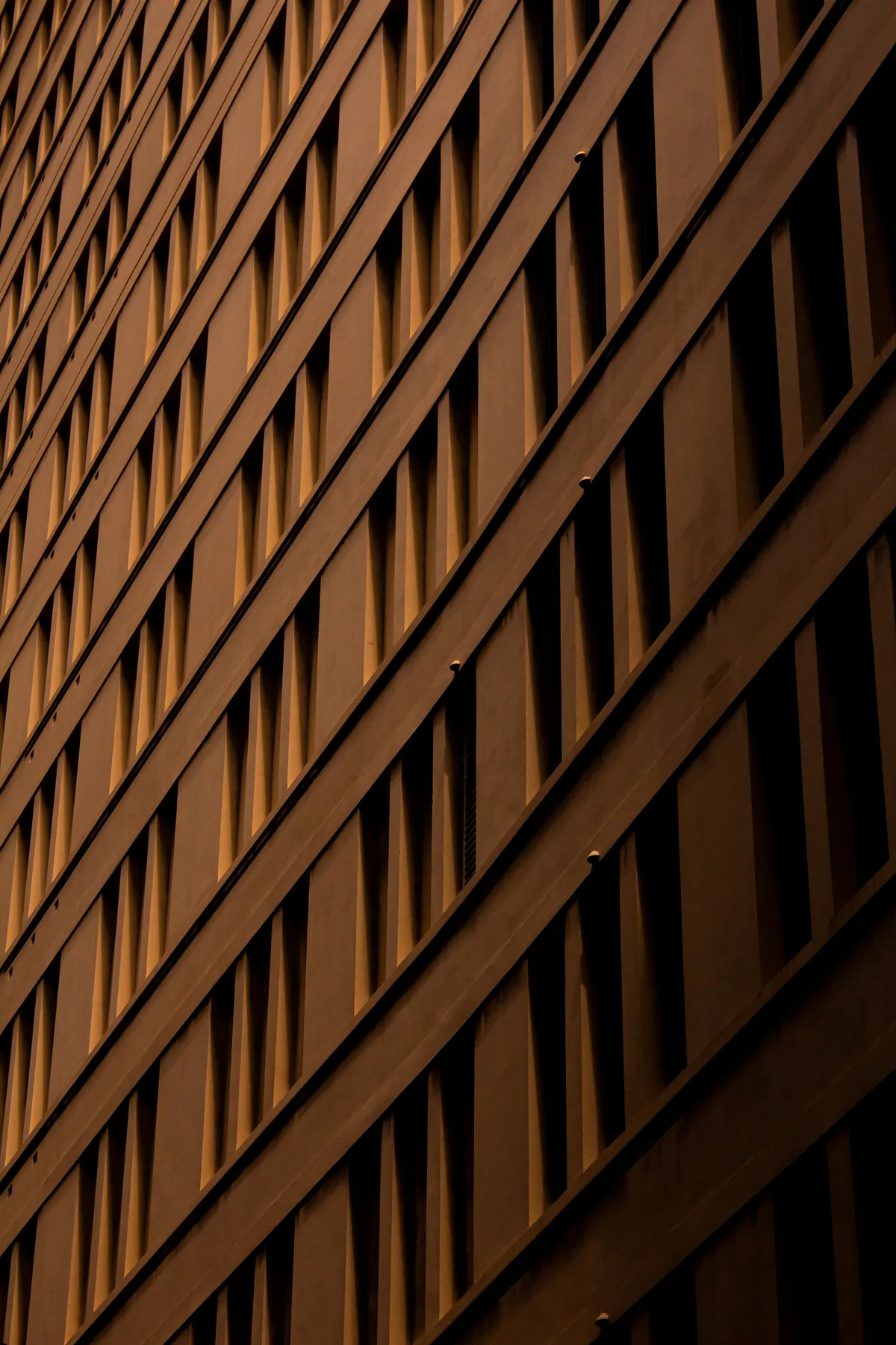 Facciata curva di un edificio con file diagonali di finestre, in luce calda
